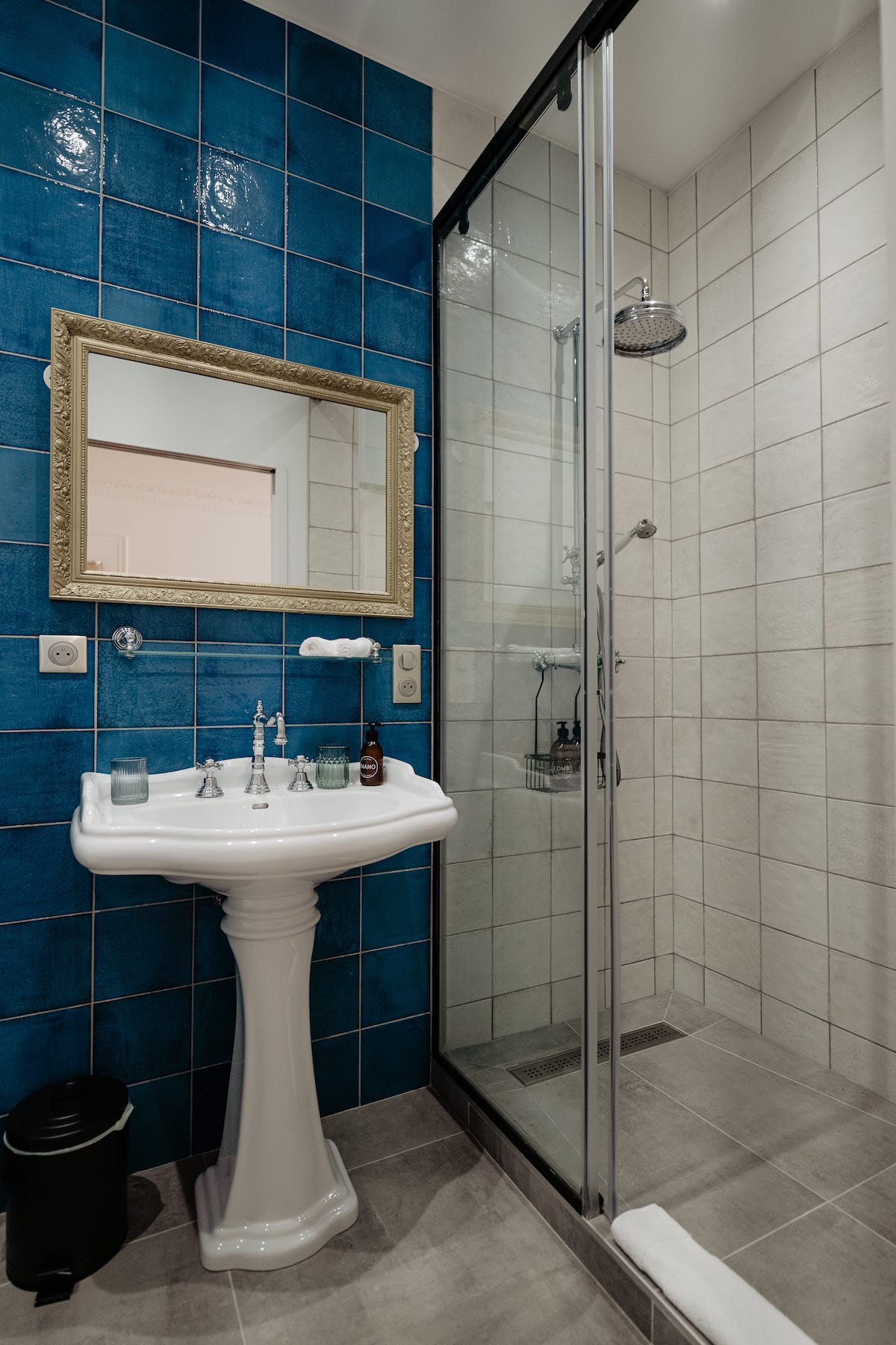Salle de bain à la faïence bleue et au lavabo blanc de la chambre rosa bonheur du château grand arnaud